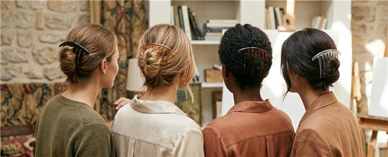 Four women showcasing elegant Fashionetiks hair combs and clips in a boutique setting